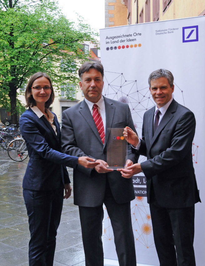 Katrin Hennig (Initiative "Land der Ideen") und Stefan Schellhorn (Deutsche Bank, rechts) überreichen Eric Hilgendorf die Auszeichnung für die Forschungsstelle RobotRecht. (Foto: Robert Emmerich)