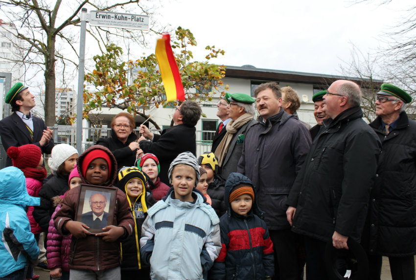 Bürgermeister Adolf Bauer und Bürgermeisterin Marion Schäfer-Blake enthüllen das Straßenschild am neuen Erwin-Kuhn-Platz am Heuchelhof. Unter den Gästen bei der Feier im Zeichen der Ökumene auch Pfarrer Alfred Kraus und Pfarrer Max von Egidy. (Foto: Georg Wagenbrenner)